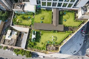 An aerial view of a building with multiple green spaces, including a central lawn and surrounding gardens.