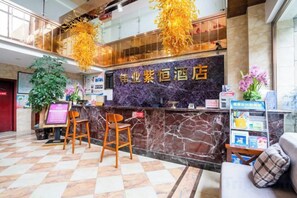 A hotel reception area with a marble counter, two wooden chairs, and a sofa. - Ziheng Hotel (Meishan)
