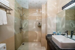 Un baño moderno con ducha de vidrio, lavamanos blanco y un perchero para toallas.