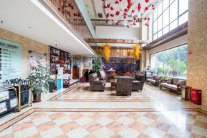 Un vestíbulo de hotel con mostrador de recepción, zona de estar y un amplio ventanal con vistas al exterior.