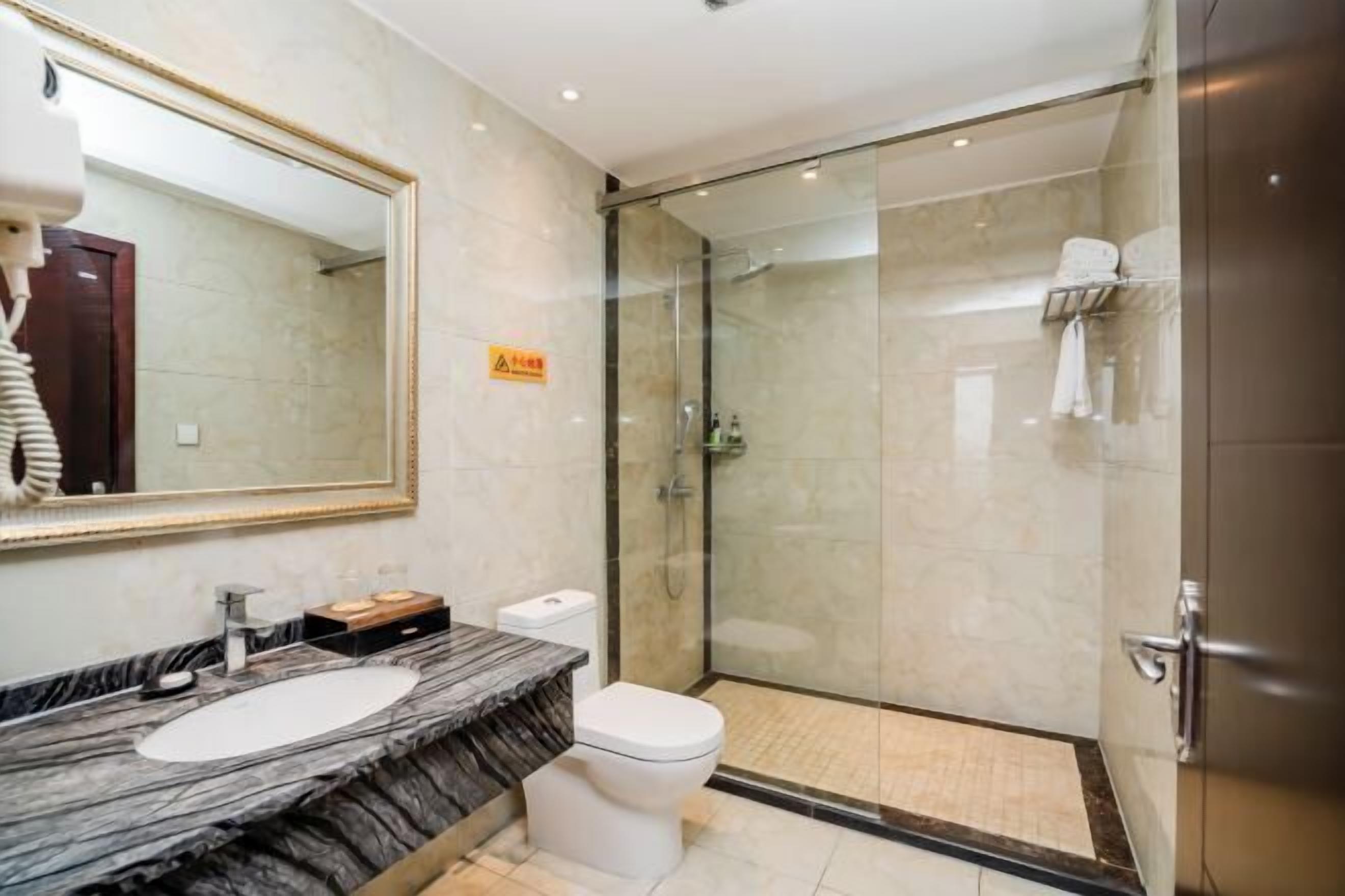 A modern bathroom with a marble sink, a toilet, and a glass-enclosed shower.