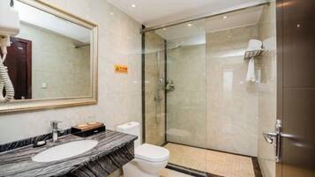 A modern bathroom with a marble sink, a toilet, and a glass-enclosed shower.