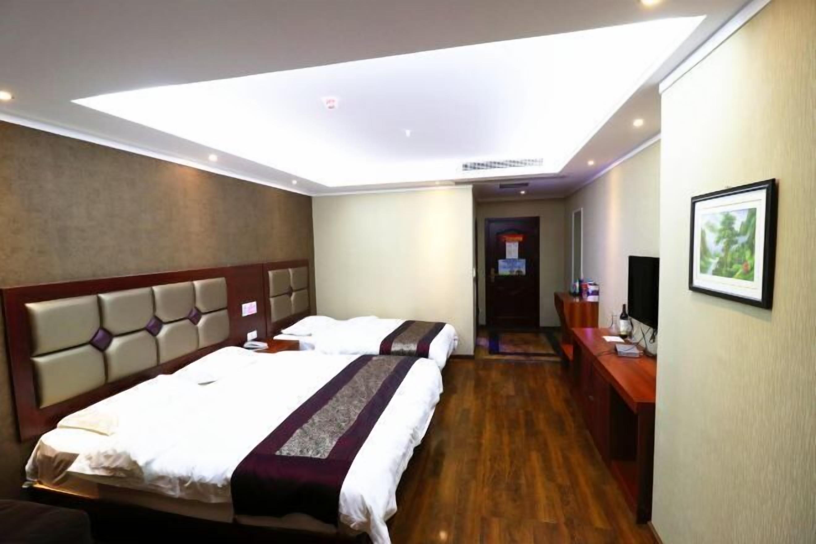 A hotel room with two beds, a desk, a chair, and a television.