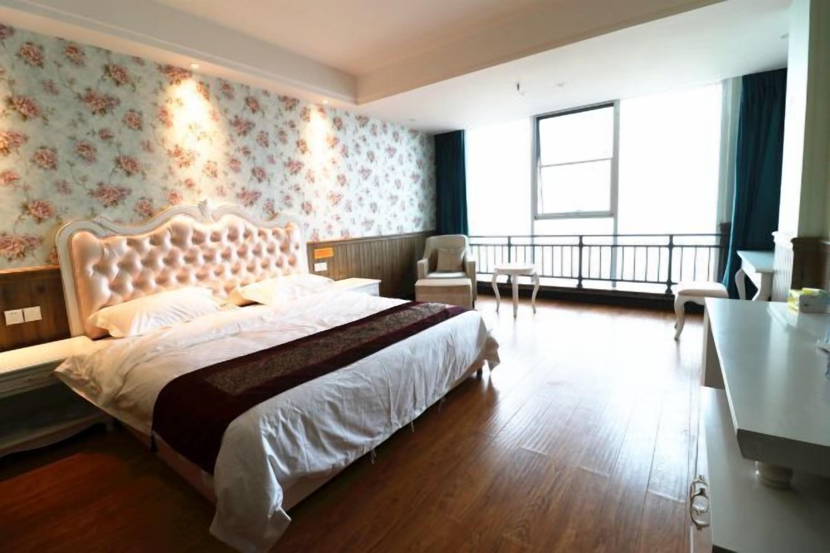 A hotel room with a large bed, a desk, and a balcony with a view.