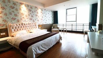 A hotel room with a large bed, a desk, and a balcony with a view.