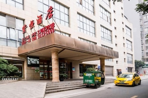 Entrada de hotel con vestíbulo techado, un taxi y un camión de reparto.