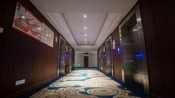 Un pasillo de hotel con alfombra estampada, paredes de madera e iluminación empotrada en el techo.