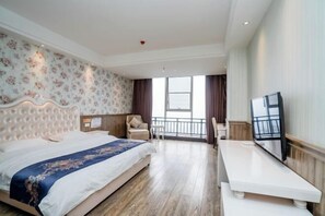 A hotel room with a large bed, a TV, a balcony, and a view of the outdoors.