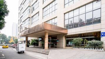 Una entrada de hotel moderna con un paseo techado, una zona de estacionamiento y una vista despejada de la calle.
