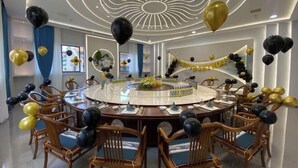 Una mesa redonda para comer con sillas, globos y un cartel que dice 'Happy Birthday'.