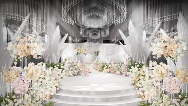 Un escenario con fondo blanco, arreglos florales y una escalera que sube hacia él.