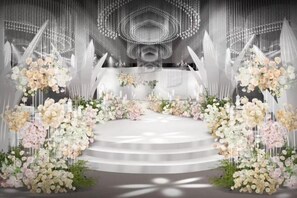 Un escenario con fondo blanco, arreglos florales y una escalera que sube hacia él.