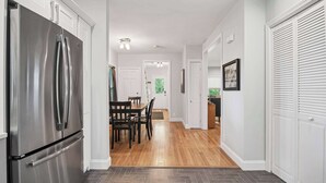 Una cocina con un refrigerador de acero inoxidable, una mesa de comedor de madera y sillas.