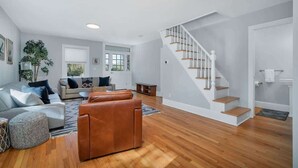 Uma sala de estar moderna com escada, piso de madeira e uma janela grande.