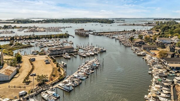 Uma marina com barcos atracados, um navio grande e edifícios ao longo da orla.