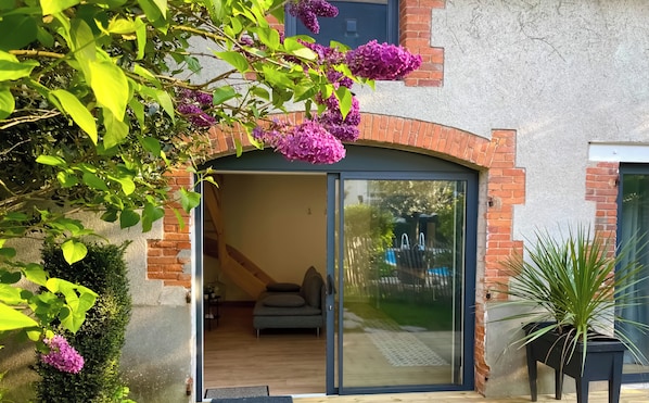 A modern house with a glass door entrance, a wooden deck, and a garden with purple flowers. - "La Boétie II" - 50 m2 de Charme Limoges Centre (Limoges)
