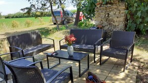 Un área de estar al aire libre con muebles de mimbre y una pequeña mesa con un florero.