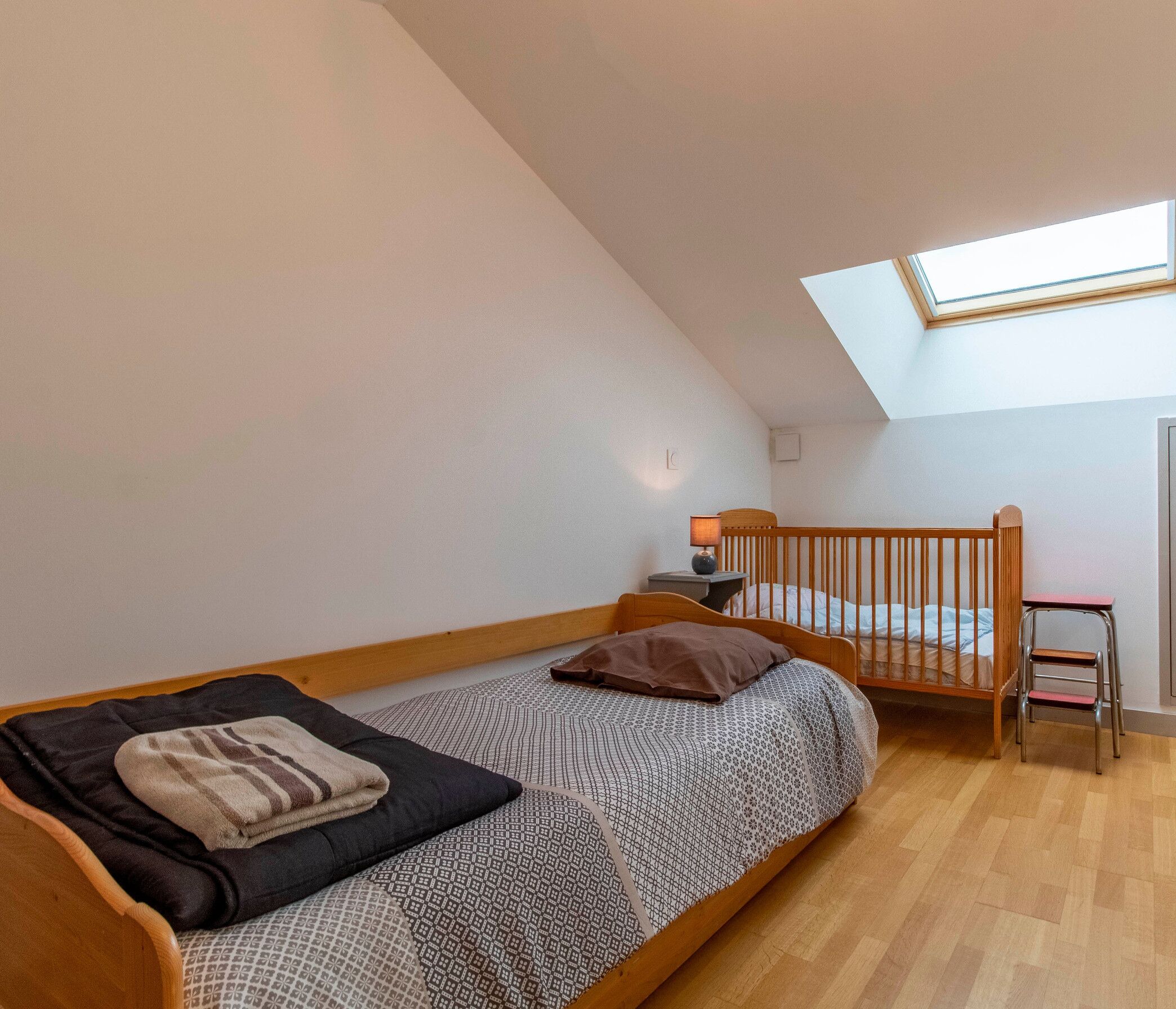 Ein kleiner, gemütlicher Raum mit Etagenbett, Schreibtisch und Dachfenster.
