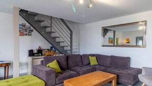 Una sala de estar moderna con un sofá gris, una mesa de centro de madera y una escalera.
