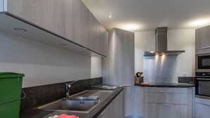 Una cocina moderna con electrodomésticos de acero inoxidable, un lavamanos doble y una campana extractora.
