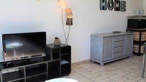 A living room with a flat-screen TV, a lamp, a cabinet, and a wall with the word "HOHE" spelled out.