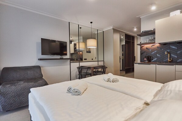 Une chambre d’hôtel avec un lit, un bureau, une chaise, une télévision et un miroir.