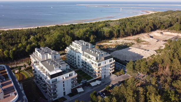 Un complesso residenziale moderno con numerosi balconi, un cortile interno e vista sul mare.