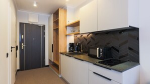 Una cucina moderna con pensili bianchi, un piano di lavoro nero e una parete di fondo rivestita con piastrelle a spina di pesce.