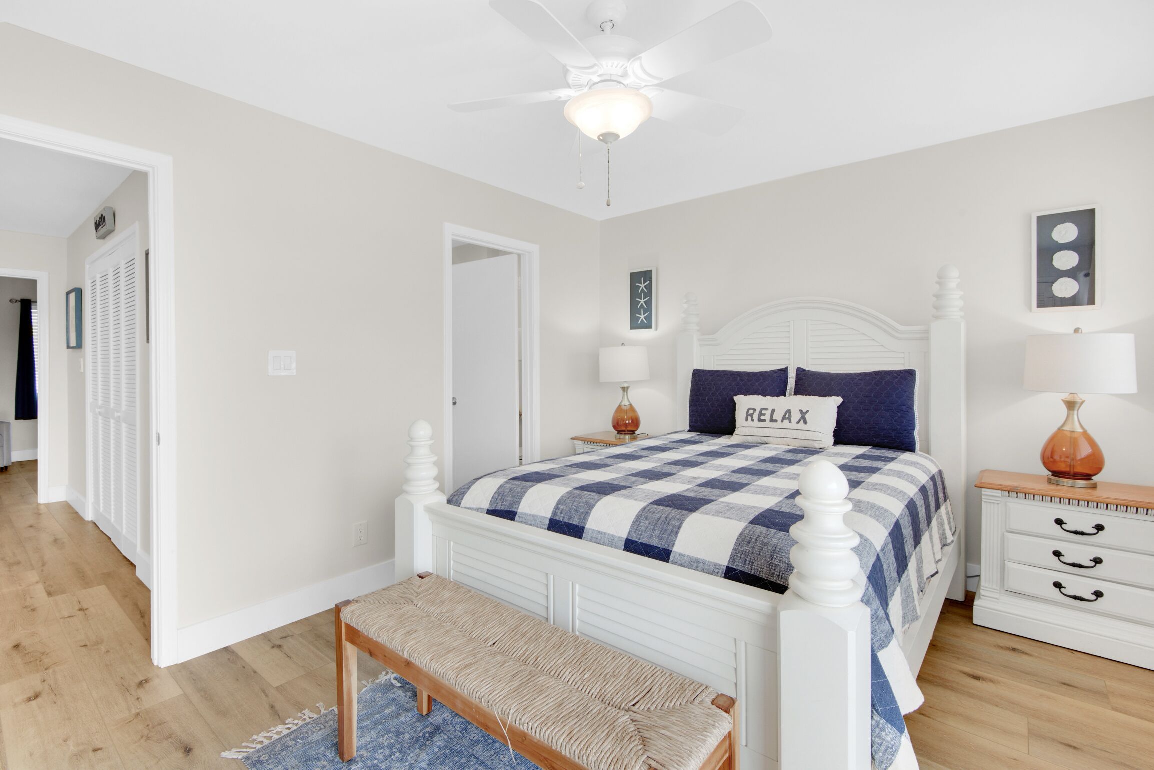 Un dormitorio con cama blanca, colcha azul y blanca a cuadros, almohada con el texto 