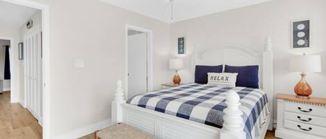 Un dormitorio con cama blanca, colcha azul y blanca a cuadros, almohada con el texto