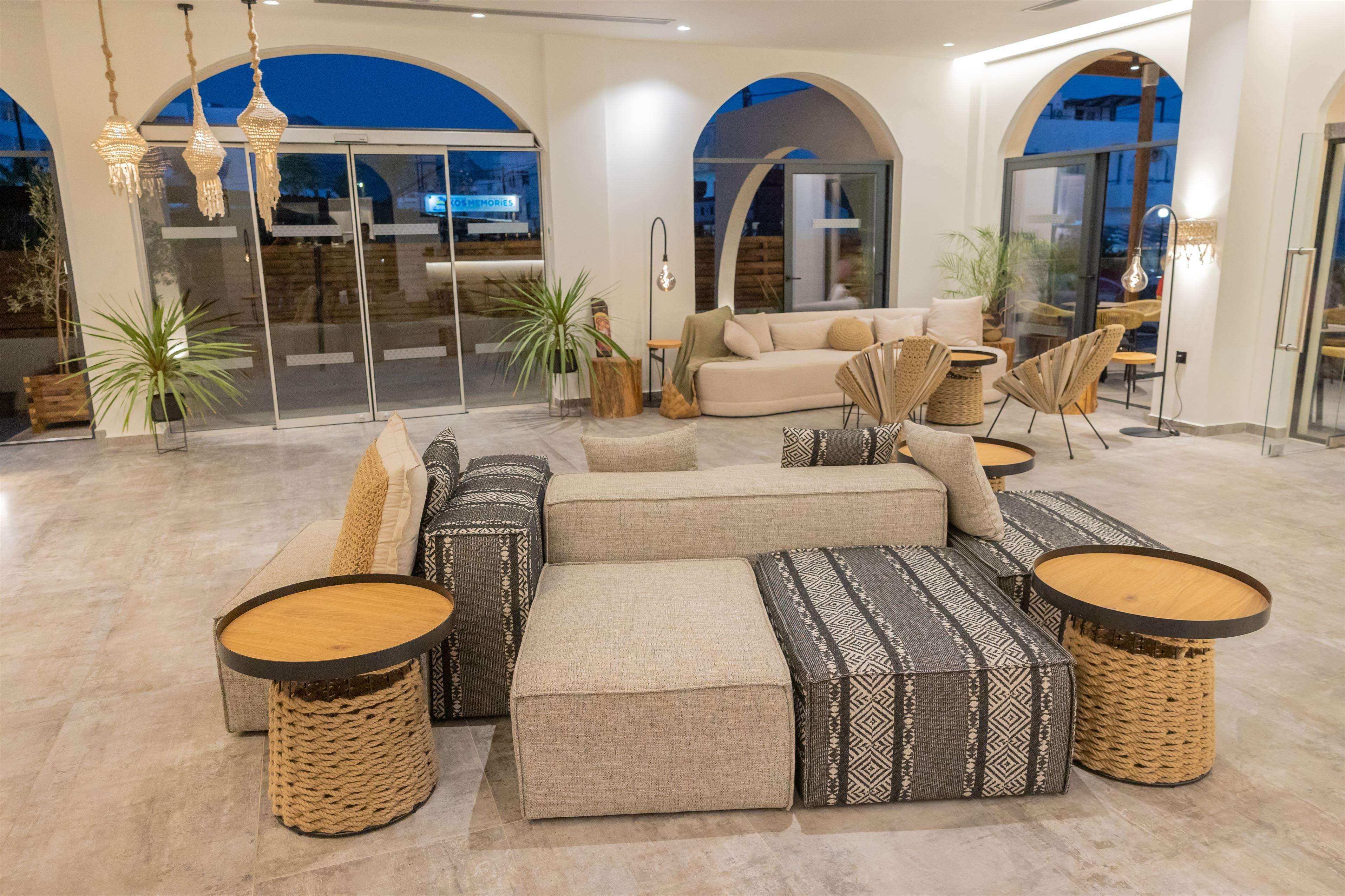 A spacious living area with a sectional sofa, multiple poufs, and round wooden tables.