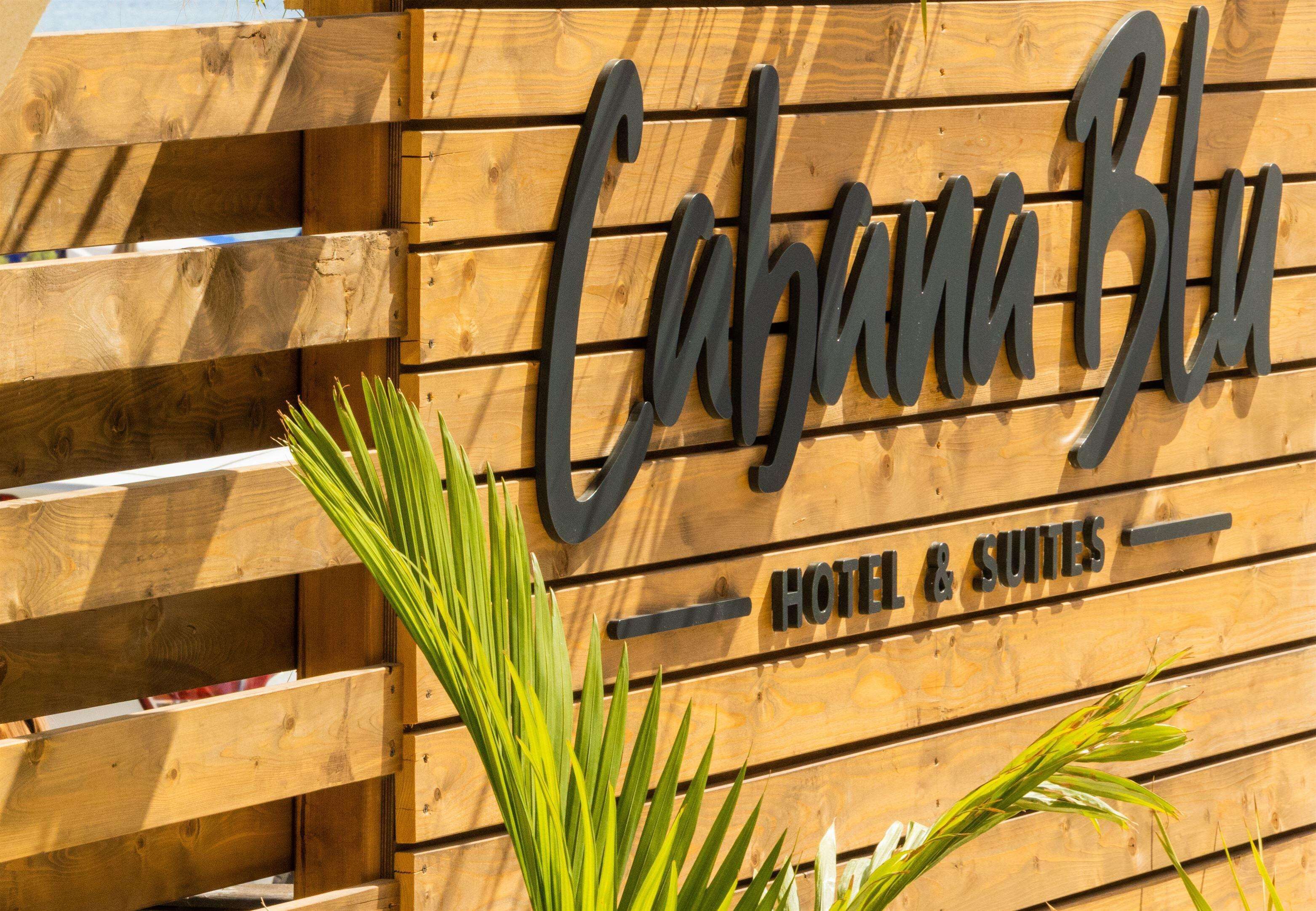 A wooden sign with the name "Cahona Blu" and the words "HOTEL & SUITES" indicating the establishment is a hotel.