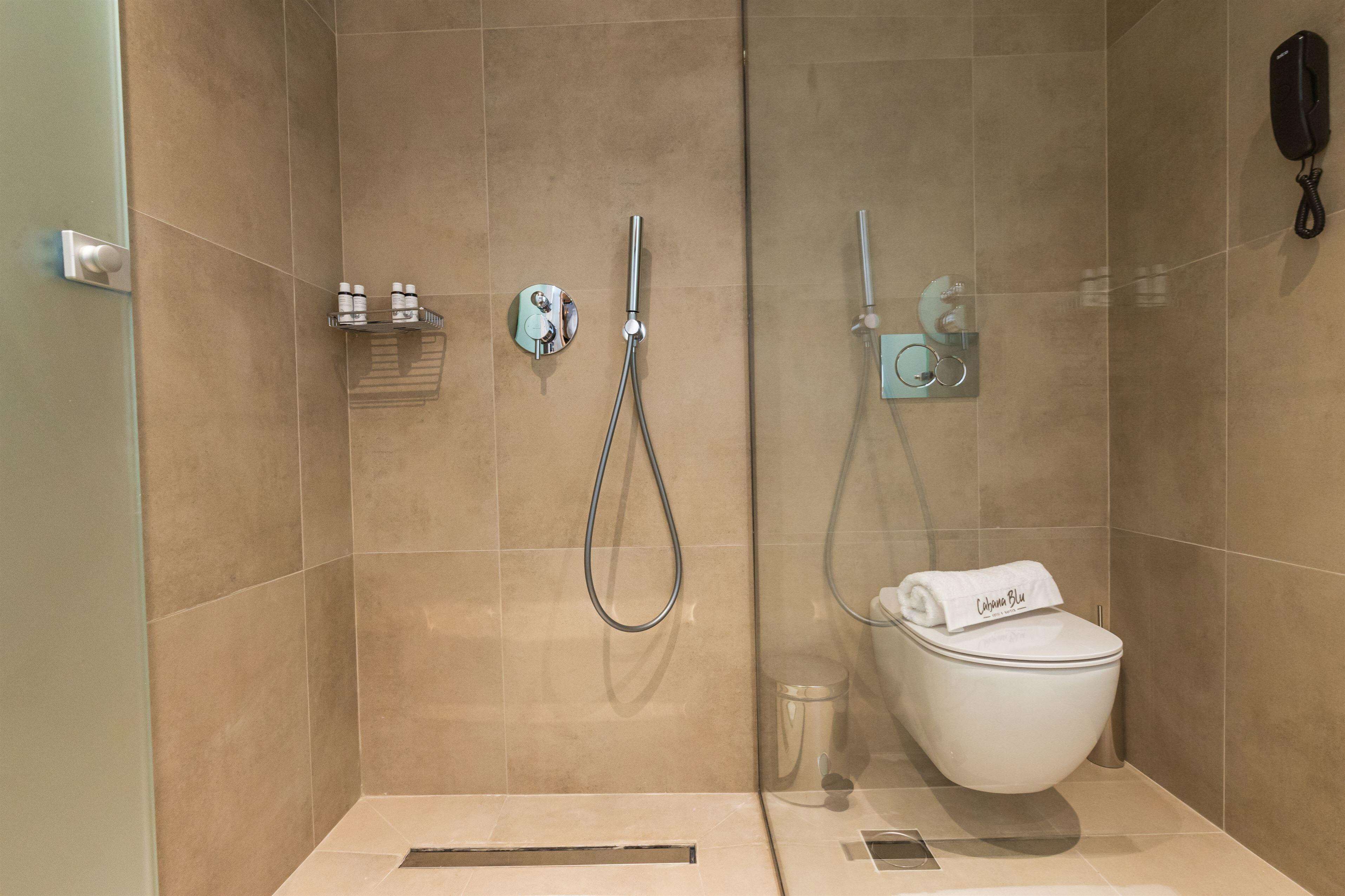 Un bagno moderno con doccia a pavimento, un water e un portasciugamani.