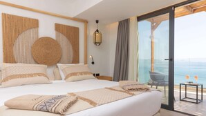 A hotel room with a large bed, a view of the sea, and a balcony with a table and chairs. - Cabana Blu Hotel & Suites (Kos)