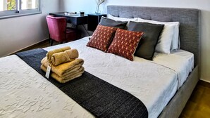 A modern hotel room with a large bed, a desk, and a view of the city. - Phaedrus Living: Seaside Residence Lighthouse 70 (Paphos)