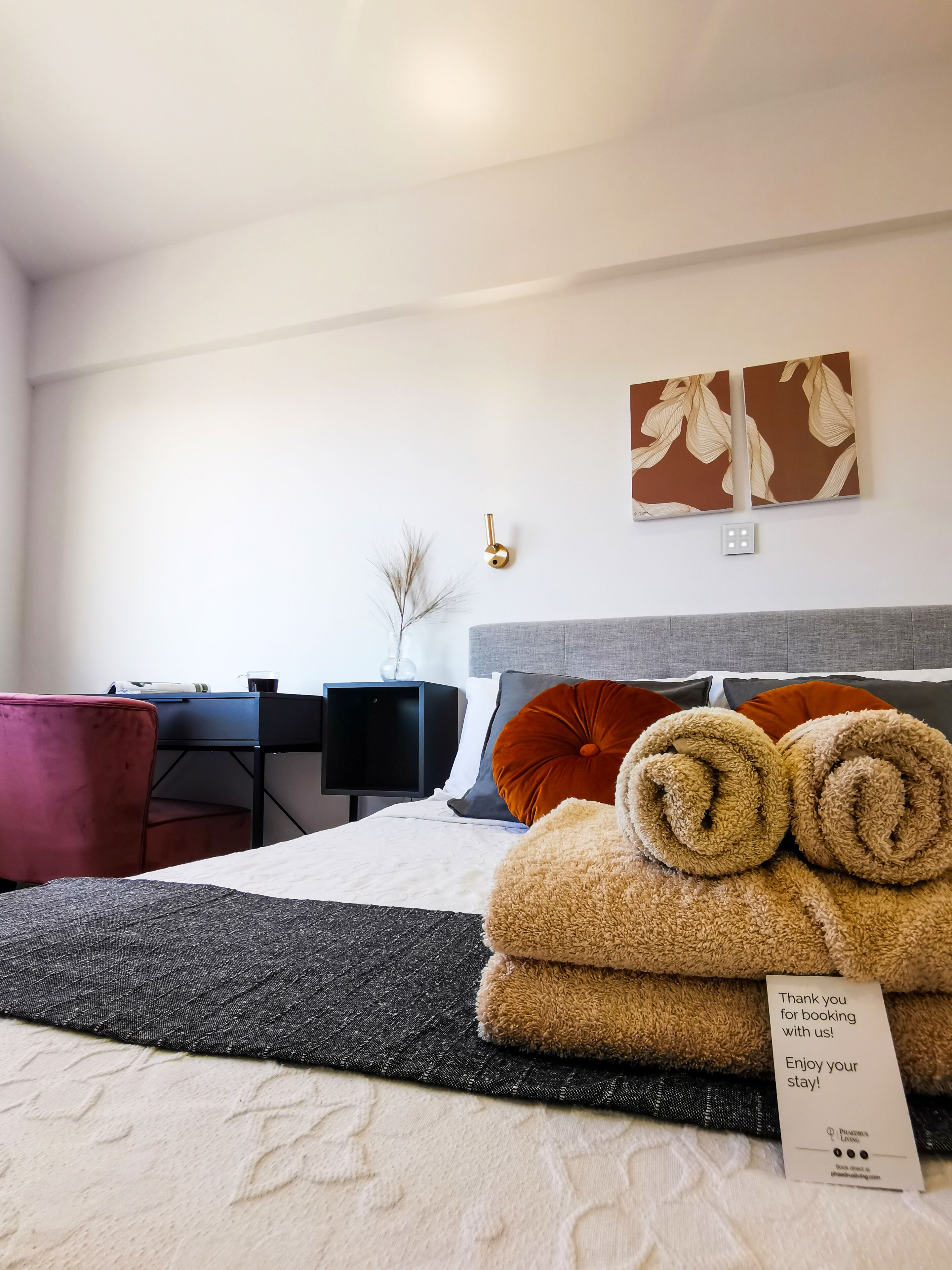 Une chambre d’hôtel avec un lit, un bureau, une chaise et des œuvres d’art accrochées au mur.