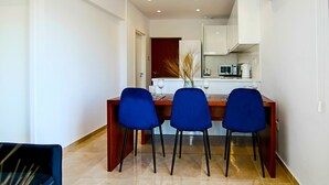 A modern dining area with a wooden table and three blue chairs. - Phaedrus Living: Seaside Residence Lighthouse 70 (Paphos)