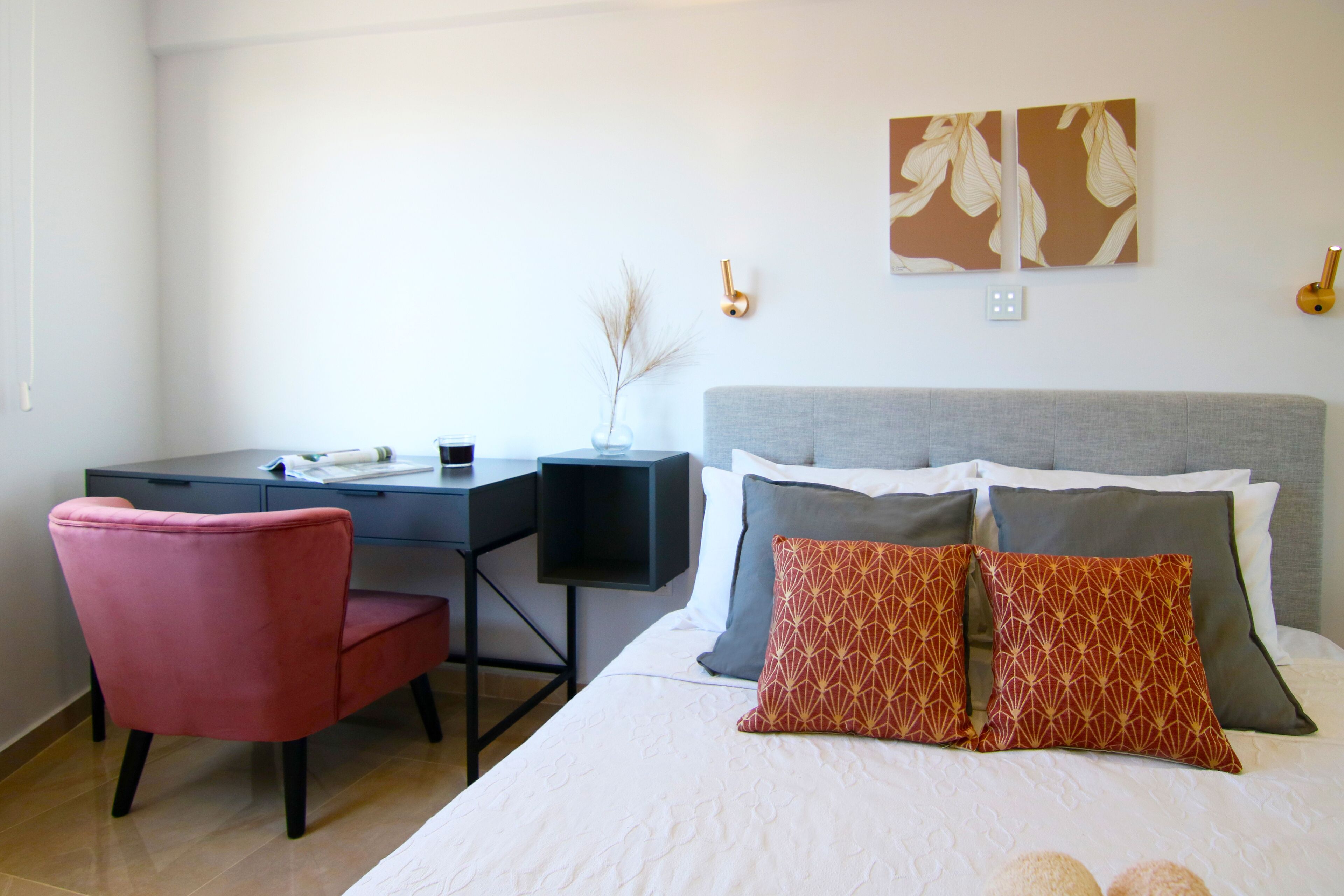 Een hotelkamer met een bed, een bureau, een stoel en twee wandlampen.