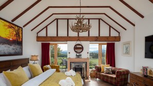 Un dormitorio espacioso con una cama grande, una chimenea, un sofá y vistas al campo.