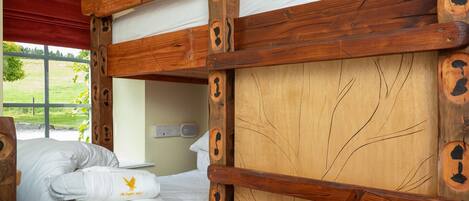 Una cama literera con barandillas de madera y una ventana con cortina roja.