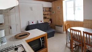 Un salón acogedor con sofá, una mesa de comedor con sillas, un microondas empotrado y una ventana que proporciona luz natural.
