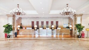 Eine großzügige Lobby mit Marmorboden, zwei Kronleuchtern und einer Rezeption.