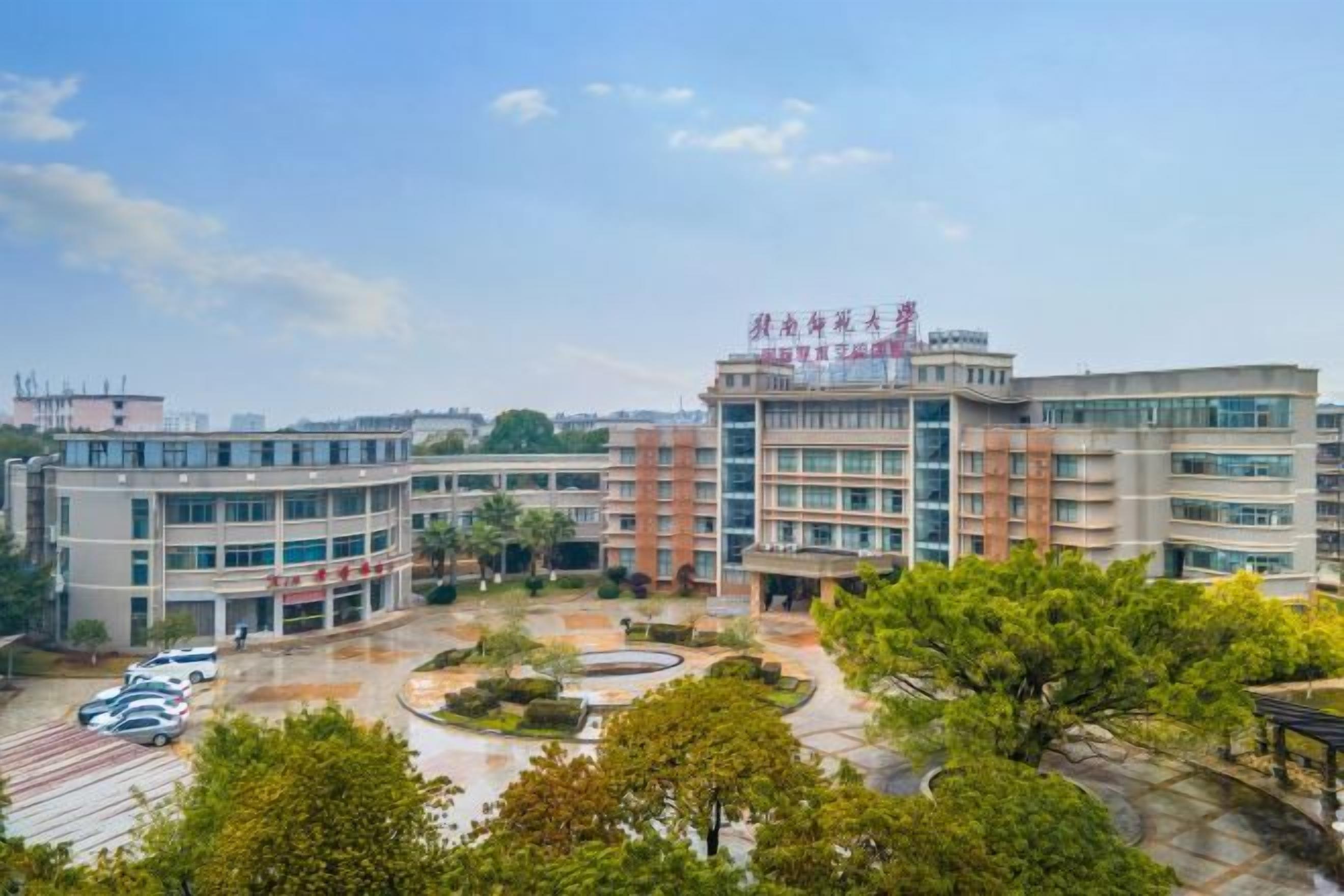 A multi-story building with a central courtyard, surrounded by trees and a parking area.