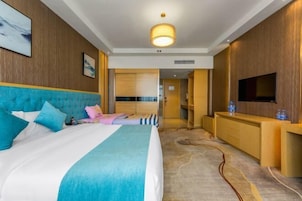 Habitación de hotel con una cama grande, televisión, escritorio y baño visible a través de una puerta abierta.