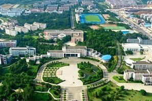 An aerial view of a campus with multiple buildings, a central courtyard, and surrounding greenery. - Gannan Normal University International Academic Exchange Center (Ganzhou)