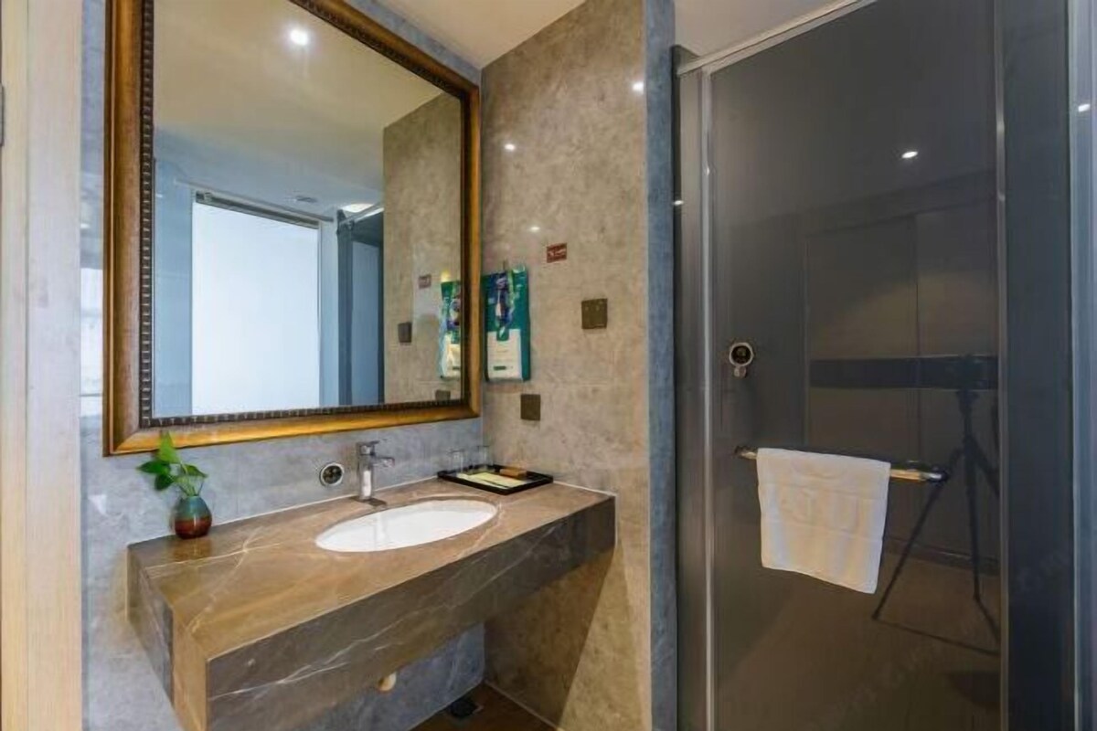 A modern bathroom with a large mirror, a sink, and a glass shower enclosure.