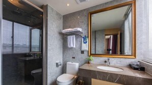 Ein modernes Badezimmer mit Duschkabine aus Glas, einer weißen Toilette, einem мраморным Waschbecken und einem großen Spiegel.