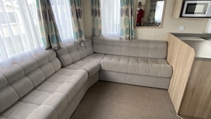 A modern living area with a sectional sofa, a small table, and a microwave.