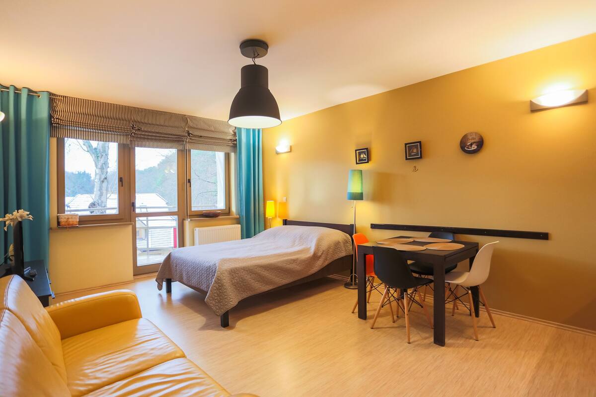 Ein Hotelzimmer mit einem Bett, einem Schreibtisch mit Stuhl, einer Couch und einem Fenster mit Vorhängen.