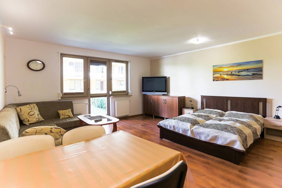Ein Zimmer mit einem Bett, einem Fernseher, einem Sofa, einem Tisch und einem Fenster.
